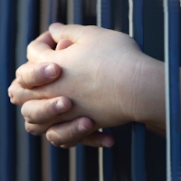 Clasped hands through prison bars. Image used under a Creative Commons By Atribution license by Harpeth Hills Church of Christ