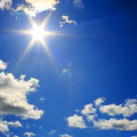 The sun is depicted in a blue sky with scattered clouds. Photgraph by flickr user truds09 and licensed under a Creative Commons By Attribution License