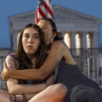 Two women sit in front of the Supreme Court of The United States building, comforting each other.. Public Doamin image.