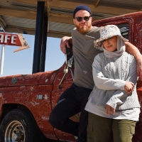 Mona and Seb stand by an antique Ford F100 pickup truck covered with grafitti outside the Mid Point Cafe. Image courtesy of Unity Productions Foundation and PBS