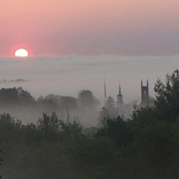 Sunrise of the center of Newtown Connecticut. The Congregational and Episcipal churches and a large flagpole are shown aganist a backdrop of morning fog. Photo credti Micheal J. McCarthy