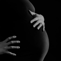A pregnant person is shown in a silhouette, with their hand resting above and below their extended abdomen.